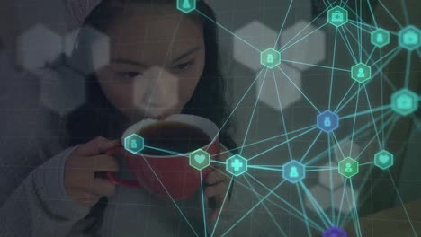 Animation-of-network-of-connections-with-icons-over-asian-woman-drinking-coffee