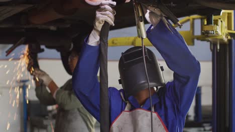Video-of-african-american-female-car-mechanic-welding-car