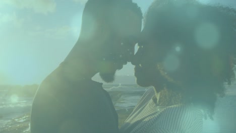 Animation-of-light-spots-over-african-american-couple-at-beach