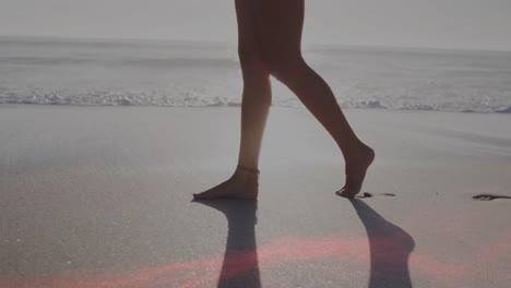 Animation-of-light-spots-over-caucasian-woman-walking-at-beach
