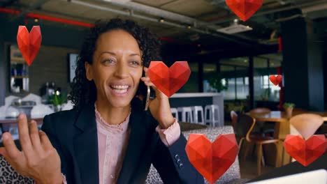 Animation-of-red-hearts-over-biracial-businesswoman-using-smartphone