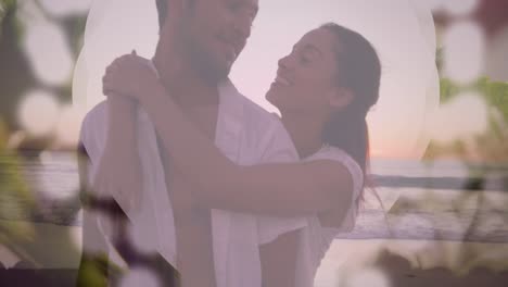 Animation-of-bokeh-over-happy-biracial-couple-hugging-and-kissing-on-beach