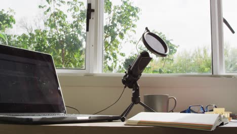 Video-Von-Laptop,-Mikrofon,-Kopfhörern-Und-Notizblock-Auf-Dem-Schreibtisch-Liegend