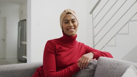 Video-De-Una-Mujer-Birracial-Feliz-Con-Hijab-Sentada-En-Un-Sofá-Y-Mirando-A-La-Cámara