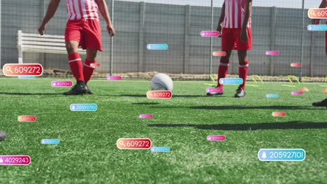 Animation-of-social-media-icons-over-mid-section-of-male-soccer-players-practicing-on-sports-field