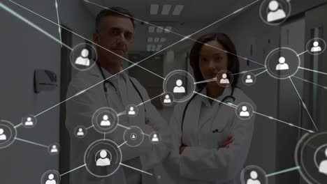 Network-of-profile-icons-against-diverse-male-and-female-doctor-standing-in-the-hospital-corridor