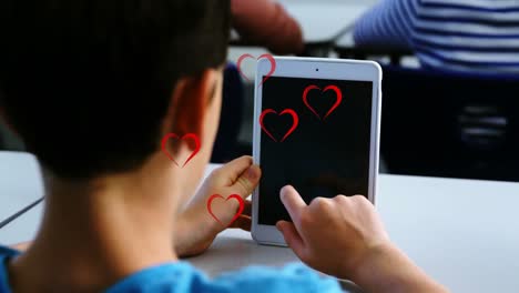Mehrere-Rote-Herzsymbole-über-Der-Rückansicht-Eines-Kaukasischen-Jungen,-Der-In-Der-Klasse-In-Der-Schule-Ein-Digitales-Tablet-Verwendet