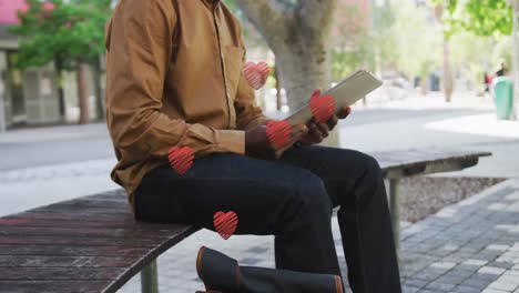 Animation-of-red-hearts-over-african-american-man-wearing-face-mask-using-tablet