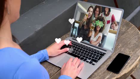 White-hearts-floating-over-caucasian-woman-having-a-videocall-on-laptop-at-a-cafe