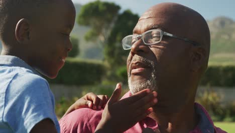 Video-of-happy-african-american-grandfather-and-grandson-spending-time-together-in-the-garden