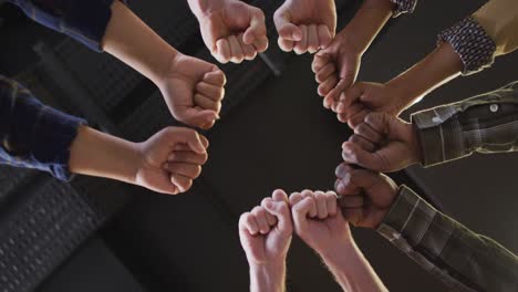 Diverse-business-people-teaming-up-with-hands-together-at-office