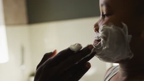 Video-of-happy-african-american-father-and-son-putting-on-shaving-foam