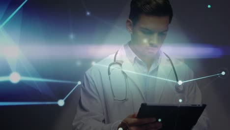 Animation-of-glowing-network-of-connections-over-caucasian-male-doctor-using-digital-tablet