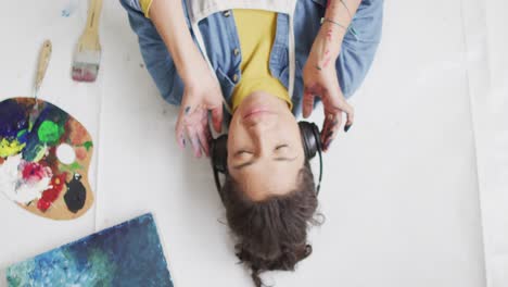 Video-of-biracial-female-artist-in-headphones-resting-in-studio