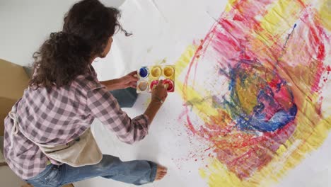 Video-of-biracial-female-artist-painting-on-floor-in-studio