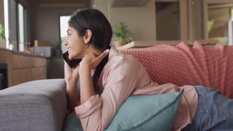 Video-of-happy-biracial-woman-lying-on-sofa-and-having-call