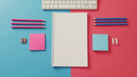 Video-of-composition-of-notebook-with-copy-space,-laptop-and-school-items-on-blue-and-pink-surface