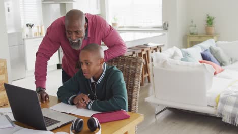 Video-of-happy-african-american-father-and-son-doing-homework-together