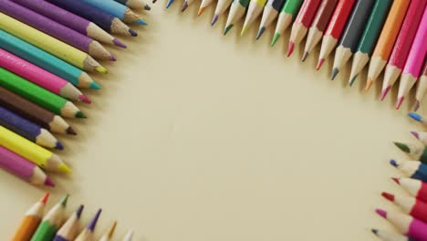 Video-of-frame-with-colorful-crayons-on-beige-surface-with-copy-space