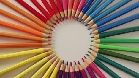 Video-of-central-composition-with-colorful-crayons-on-white-surface