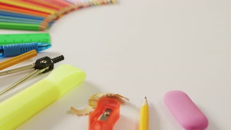 Video-of-composition-with-colorful-crayons-and-school-equipment-on-white-surface-with-copy-space