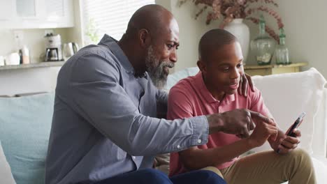 Video-of-happy-african-american-father-and-son-using-smartphone-together