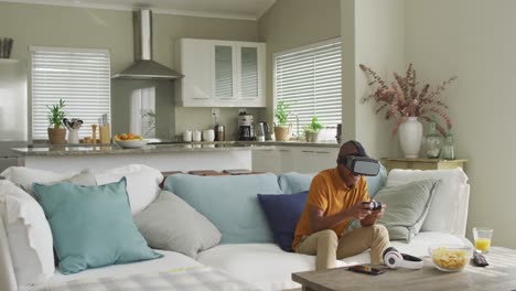 Video-Eines-Glücklichen-Afroamerikanischen-Jungen,-Der-Ein-VR-Headset-Benutzt-Und-Zu-Hause-Videospiele-Spielt