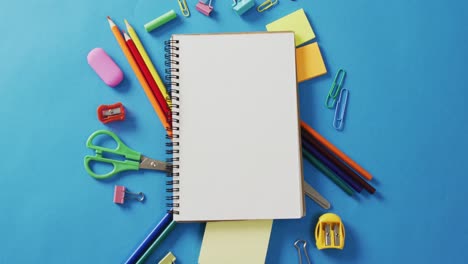 Video-of-notebook-with-copy-space-and-school-equipment-on-blue-background