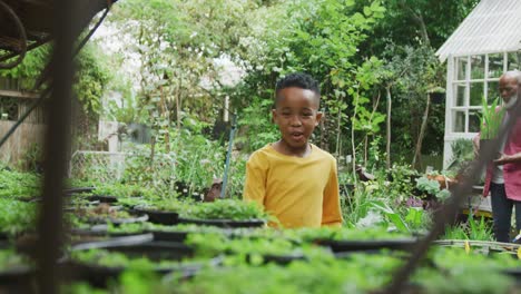 Happy-senior-african-american-man-with-his-grandson-working-in-garden