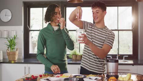 Happy-diverse-male-couple-making-healthy-drink-together-in-kitchen