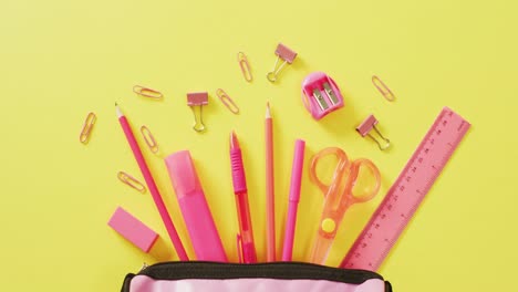 Video-of-pink-school-accessories-in-pink-case-on-yellow-surface