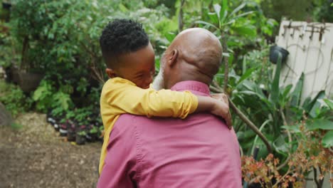 Glücklicher-älterer-Afroamerikanischer-Mann-Mit-Seinem-Enkel,-Der-Sich-Im-Garten-Umarmt