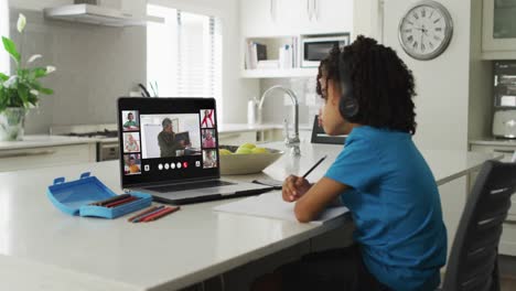 Niño-Afroamericano-Usando-Una-Computadora-Portátil-Para-Videollamadas,-Con-Un-Maestro-Y-Una-Clase-En-La-Pantalla