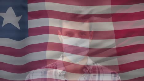 Animation-of-flag-of-liberia-over-biracial-man-in-face-mask