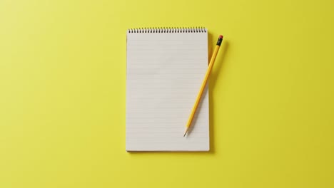 Video-of-notebook-with-copy-space-and-pencil-on-yellow-background