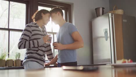 Happy-diverse-male-couple-drinking-coffee-and-embracing-in-kitchen
