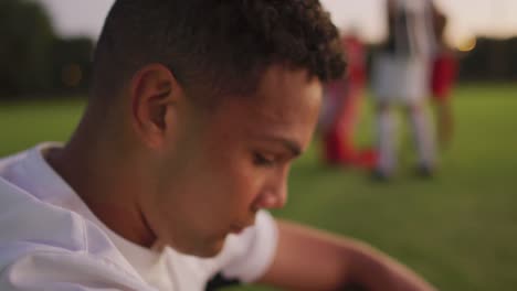 Video-of-sad-biracial-football-player-siting-on-field