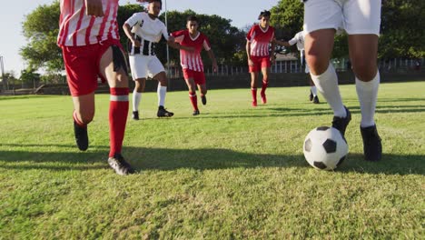 Video-Einer-Vielfältigen-Gruppe-Männlicher-Fußballspieler-Auf-Dem-Feld,-Die-Fußball-Spielen