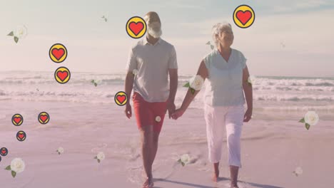 Animation-of-falling-hearts-over-african-american-senior-couple-on-the-beach