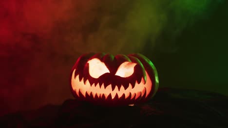 Video-of-halloween-carved-pumpkin-with-smoke-and-green-and-red-light-on-black-background