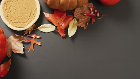 Video-of-autumn-leaves,-pumpkin-and-pie-on-black-background