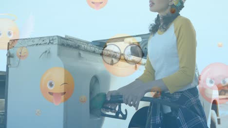Animation-of-emoji-icons-over-biracial-woman-fueling-car