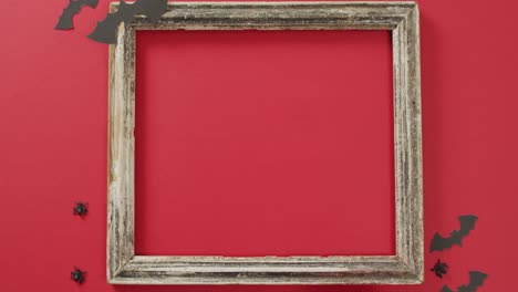 Video-of-frame-with-copy-space,-halloween-decorations-on-red-background