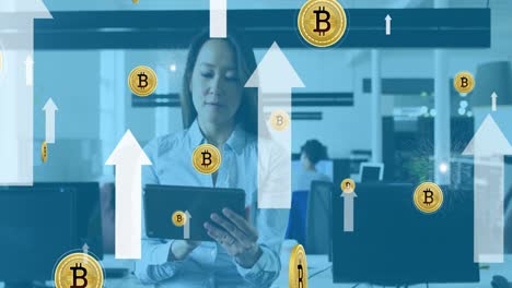 Animation-of-bitcoins-and-arrow-over-asian-woman-using-tablet-in-office