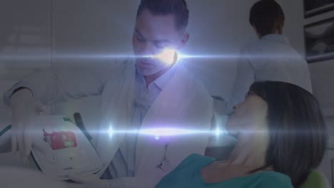 Animation-of-light-spots-over-caucasian-male-doctor-talking-with-patient