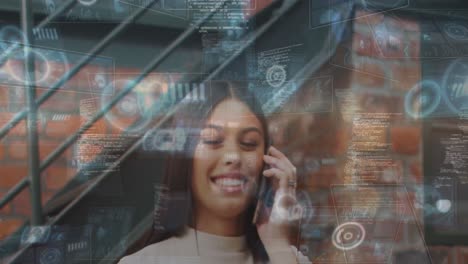 Animation-of-data-on-digital-screen-over-happy-biracial-woman-having-call-in-office