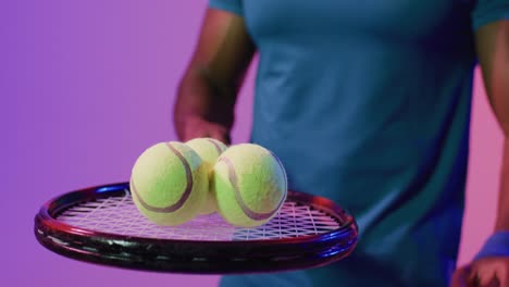 Video-of-midsection-of-african-american-male-tennis-player-bouncing-ball-in-neon-pink-lightning