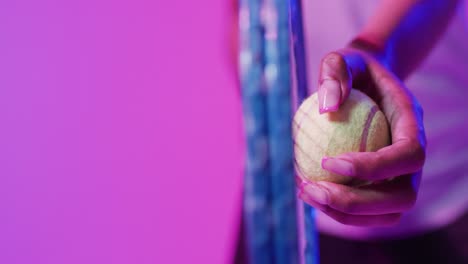 Video-of-hands-of-african-american-female-tennis-player-holding-ball-in-neon-pink-lightning