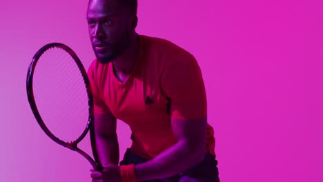 Video-of-focused-african-american-male-tennis-player-on-neon-pink-lightning