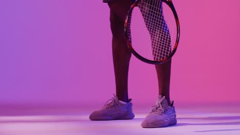 Video-of-low-section-of-african-american-male-tennis-player-bouncing-ball-in-neon-pink-lightning